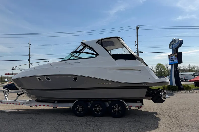 Slide: The Image of 2019 Rinker EX 320 boat on trailer in parking lot under clear sky. - 69