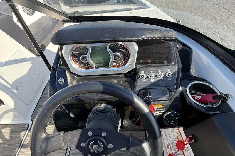 Slide: The Image of 2024 Scarab 195 ID boat dashboard with steering wheel, gauges, and control switches. - 13