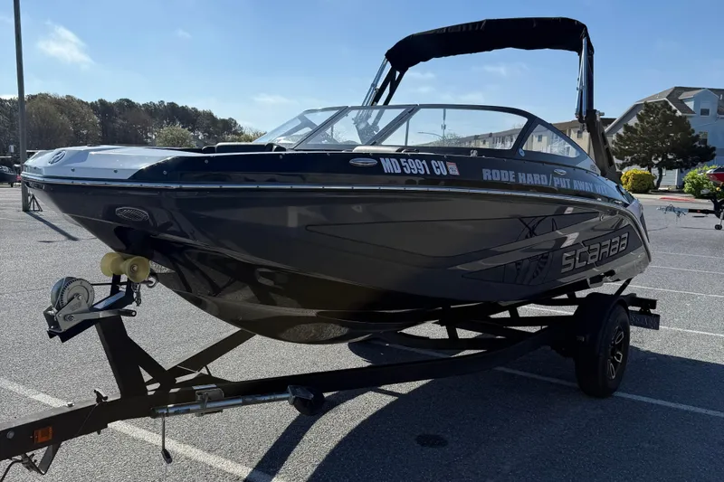 Slide: The Image of 2024 Scarab 195 ID boat on trailer in parking lot, sunny day. - 4