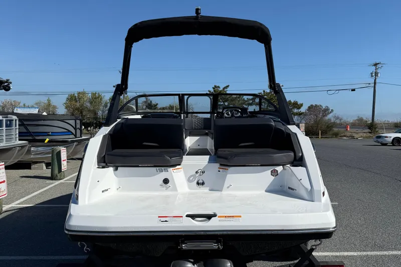 Slide: The Image of 2024 Scarab 195 ID boat, rear view, parked outdoors under clear blue sky. - 7
