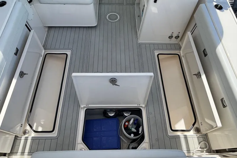 Slide: The Image of 2023 Cobia 280 Dual Console boat deck with open storage compartments. - 14