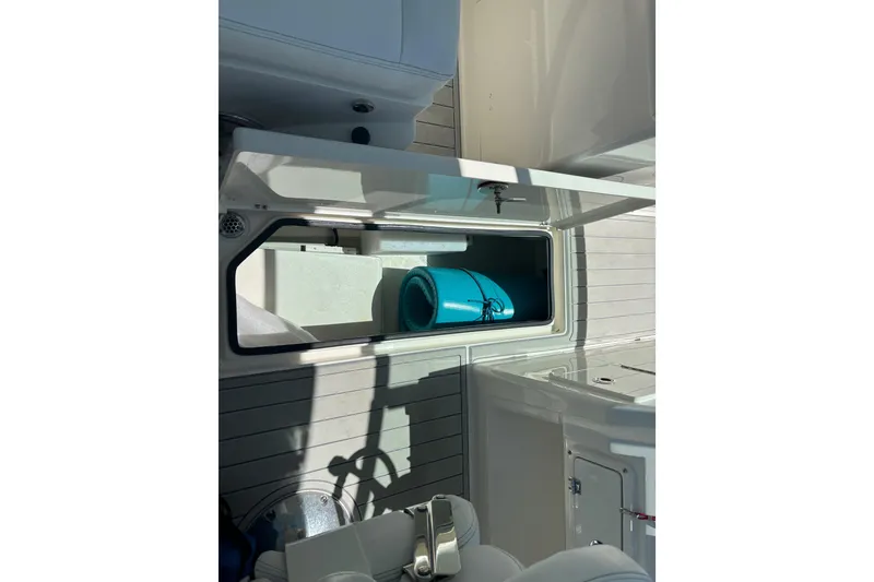 Slide: The Image of 2023 Cobia 280 Dual Console boat storage compartment with blue mat inside. - 15