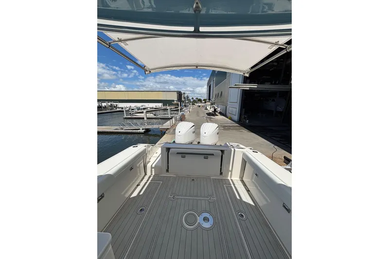 Slide: The Image of 2023 Cobia 280 Dual Console boat docked at marina, showcasing spacious deck and twin engines. - 19
