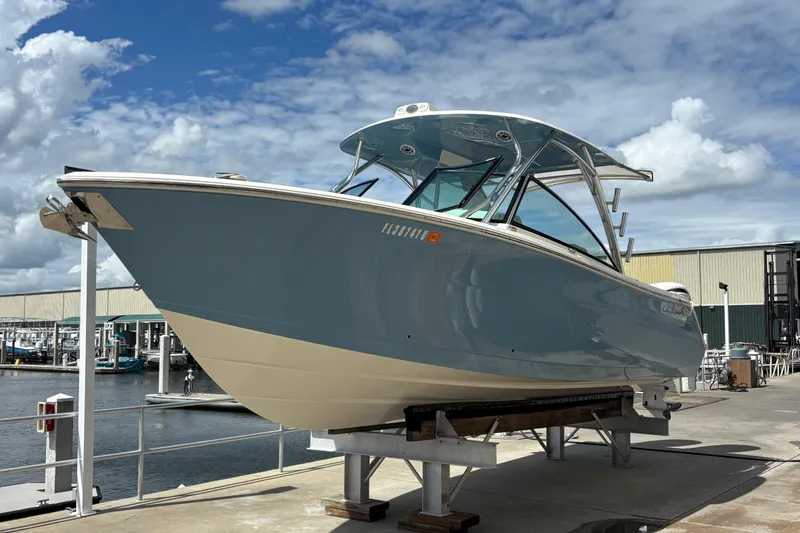 Slide: The Image of 2023 Cobia 280 Dual Console boat on display at marina under blue sky. - 2