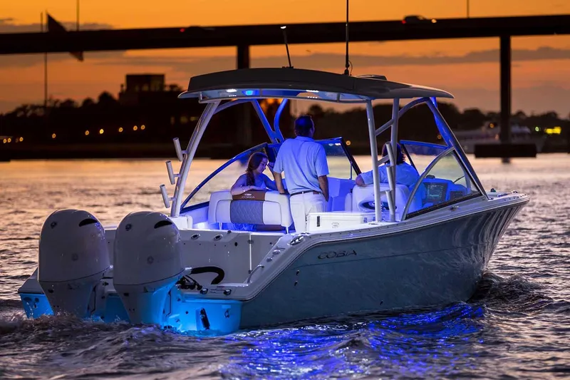 Slide: The Image of Manufacturer Provided Image: 2023 Cobia 280 Dual Console boat cruising at sunset with blue LED lights. - 23