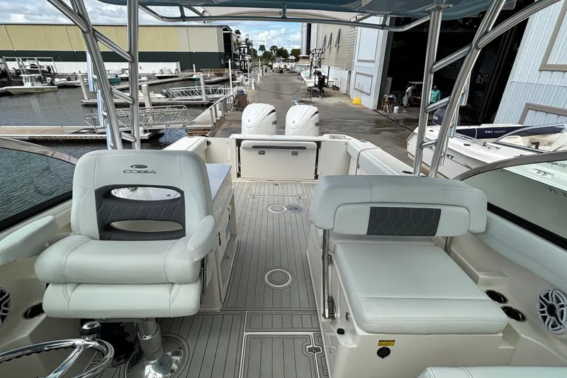 Slide: The Image of 2023 Cobia 280 Dual Console boat interior at marina, featuring seating and helm. - 7