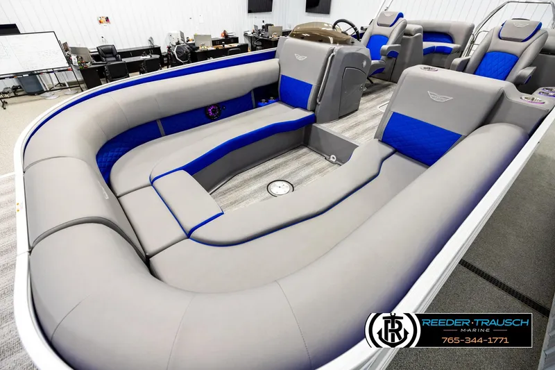 Slide: The Image of 2025 Bennington LTFBSE pontoon boat interior with gray and blue seating in showroom. - 10