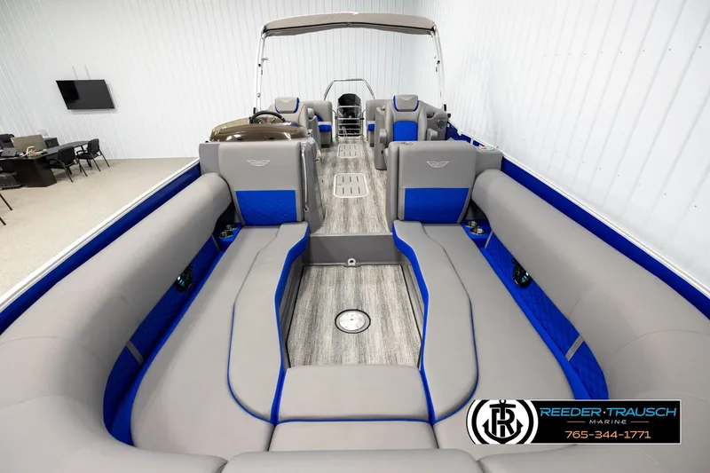 Slide: The Image of 2025 Bennington LTFBSE pontoon boat interior with gray and blue seating, in showroom. - 13