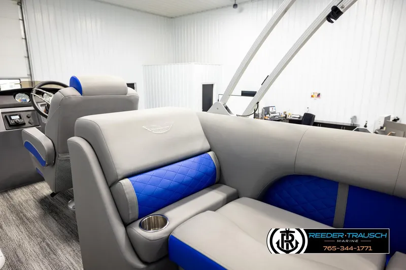 Slide: The Image of 2025 Bennington LTFBSE boat interior with gray and blue seating, cup holder, and steering console. - 25