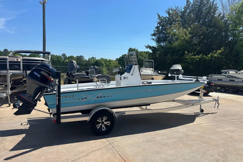Slide: The Image of 2026 Xpress H20B Bay boat on trailer outside service center. - 2