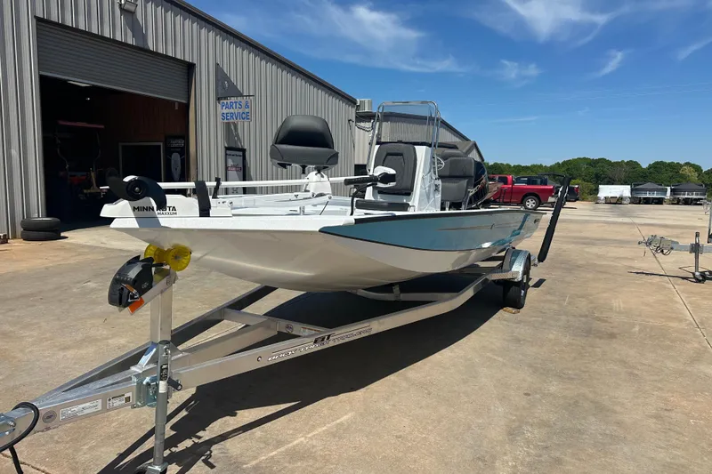 Slide: The Image of 2026 Xpress H20B Bay boat with outboard motor, parked outdoors near a metal building. - 4