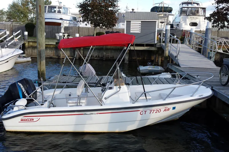 The Image of 2000 Boston Whaler Dauntless 16 boat docked with red canopy and Mercury outboard motor. - 0