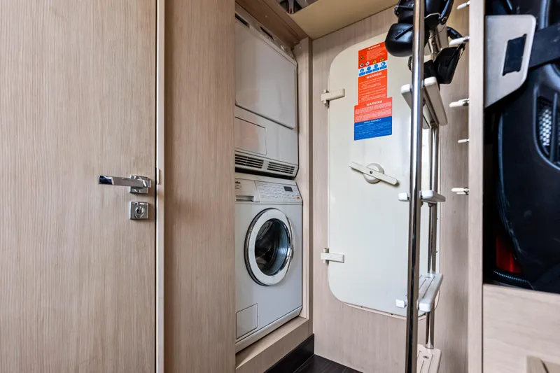 Slide: The Image of Laundry area inside 2017 Azimut Fly 72 yacht, featuring a stacked washer and dryer. - 79