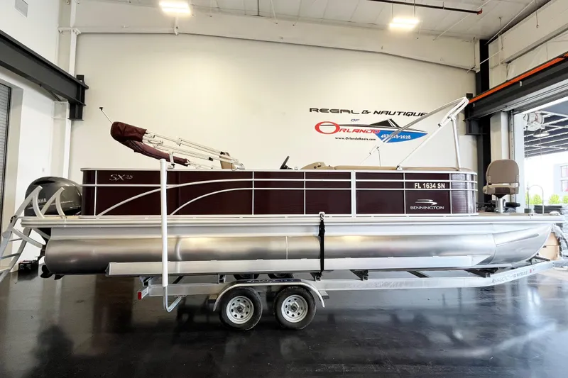 The Image of 2020 Bennington SX25 pontoon boat on trailer in showroom setting. - 1