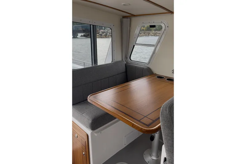 Slide: The Image of Interior of 2026 Seaport Commander 2800 boat with wooden table and gray seating. - 10