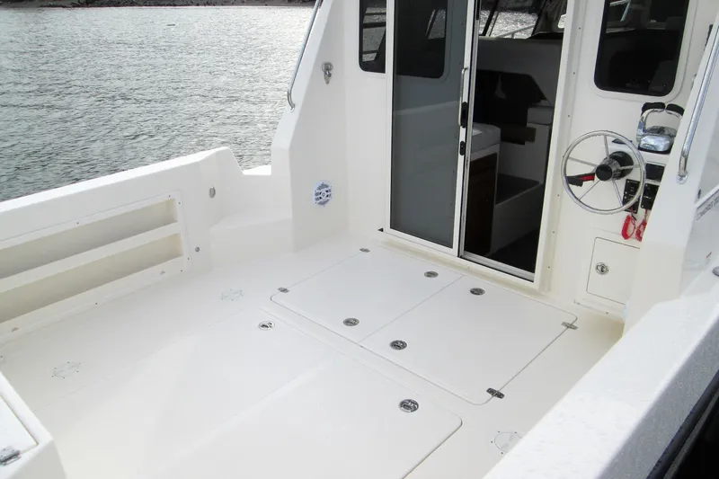 Slide: The Image of 2026 Seaport Commander 2800 boat deck with steering wheel and cabin entrance. - 24