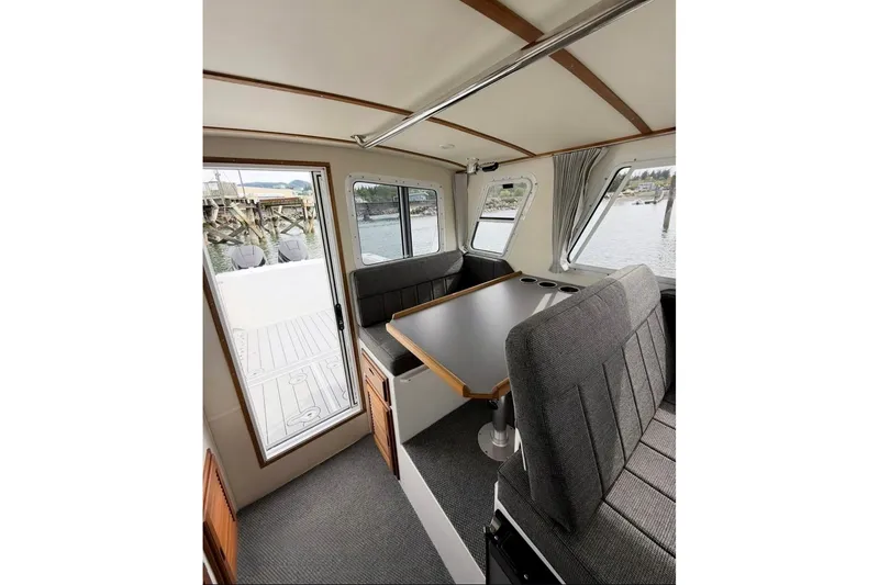Slide: The Image of Interior of 2026 Seaport Commander 2800 boat with seating and table, dockside view. - 9