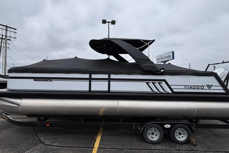 The Image of 2026 Viaggio D26U pontoon boat with cover on trailer, parked outdoors. - 1