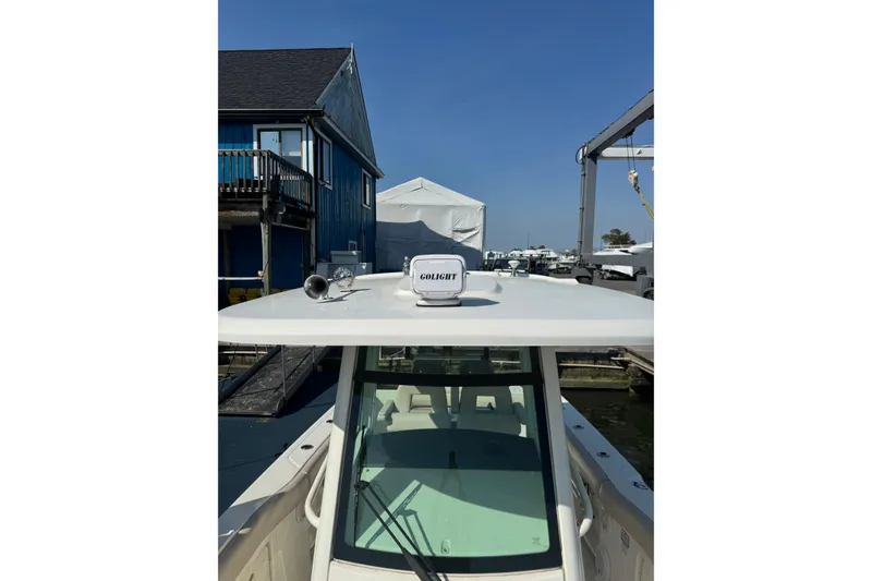 Slide: The Image of 2020 Boston Whaler 280 Outrage boat docked, featuring a Golight spotlight on the roof. - 15