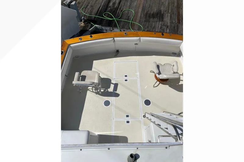 Slide: The Image of 1971 Pacifica 44 Convertible boat deck with two chairs, wooden trim, and docked at a marina. - 24