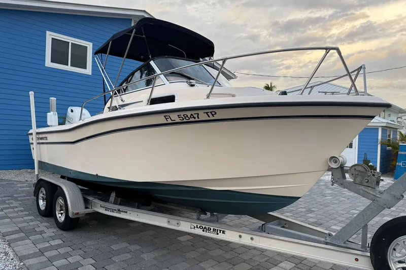 Slide: The Image of 1998 Grady-White Adventure 208 boat on trailer, parked beside a blue house. - 2