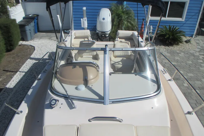 Slide: The Image of 1998 Grady-White Adventure 208 boat with seating and windshield, parked near a blue house. - 28