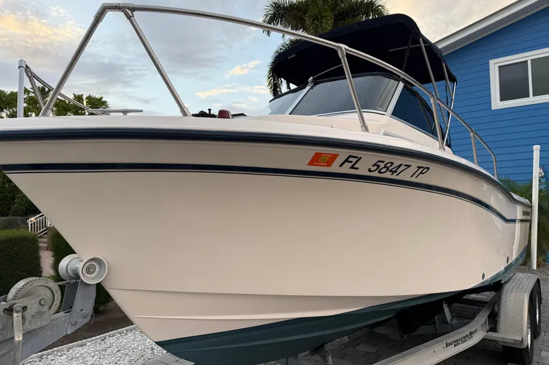 Slide: The Image of 1998 Grady-White Adventure 208 boat on trailer, parked near a blue house. - 4