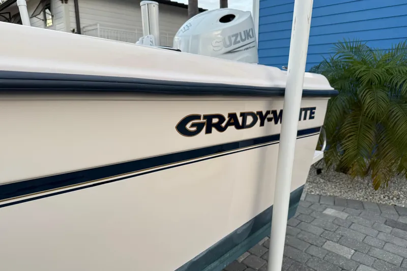 Slide: The Image of 1998 Grady-White Adventure 208 boat with Suzuki engine, parked near blue building and palm plants. - 6