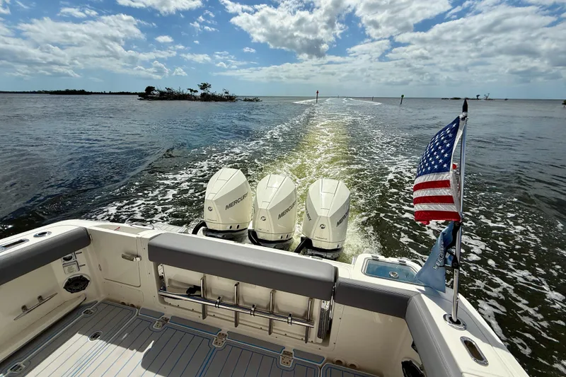 Slide: The Image of Boston Whaler 350 Realm 2025 cruising with triple Mercury engines and American flag. - 16