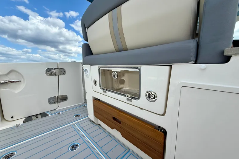 Slide: The Image of 2025 Boston Whaler 350 Realm boat interior with seating and storage, under a blue sky. - 17
