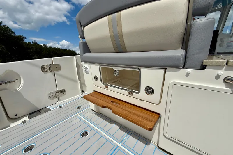 Slide: The Image of 2025 Boston Whaler 350 Realm boat interior with seating and storage under a sunny sky. - 18