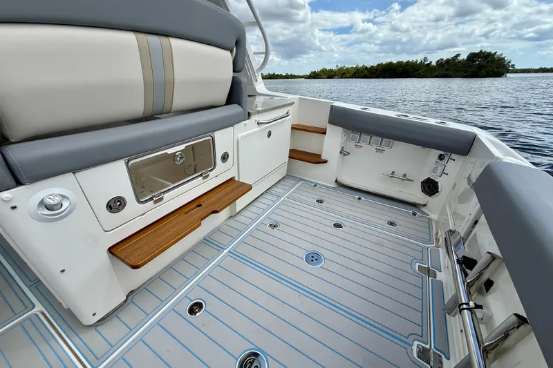 Slide: The Image of 2025 Boston Whaler 350 Realm boat interior with seating and storage, on a calm lake. - 19
