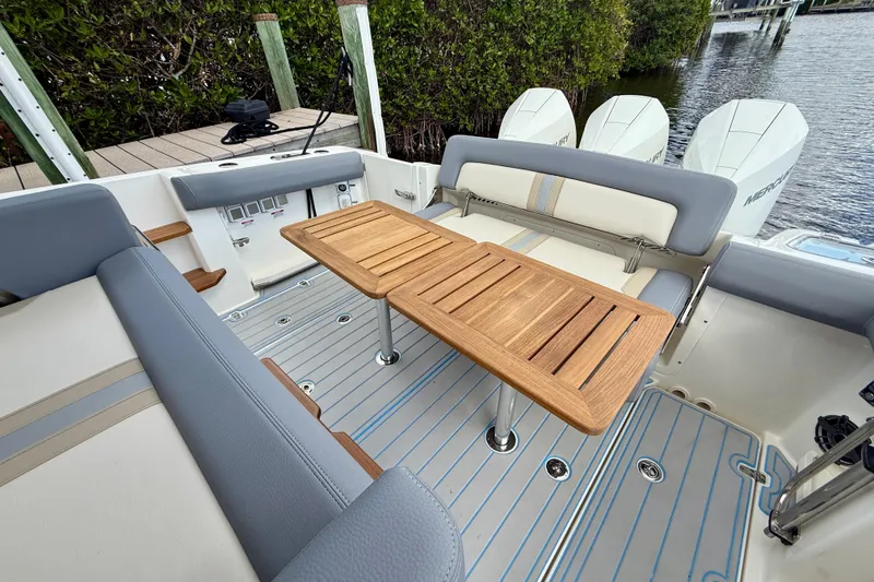 Slide: The Image of 2025 Boston Whaler 350 Realm interior with wooden table and cushioned seating. - 22