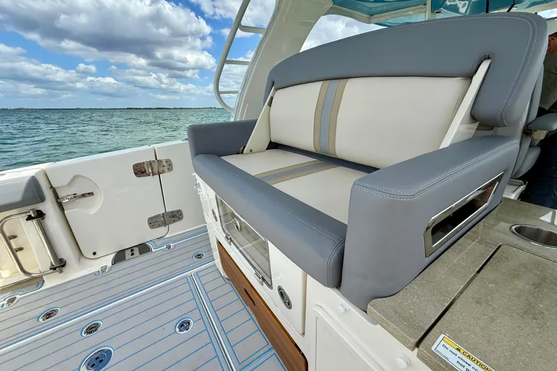 Slide: The Image of 2025 Boston Whaler 350 Realm boat interior with cushioned seating and ocean view. - 26