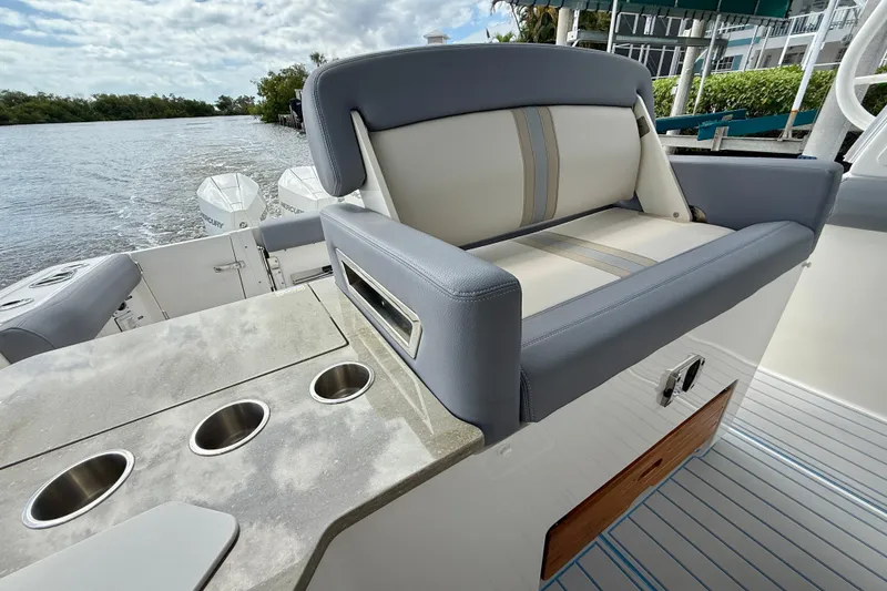 Slide: The Image of 2025 Boston Whaler 350 Realm boat interior with seating and cup holders by the water. - 27