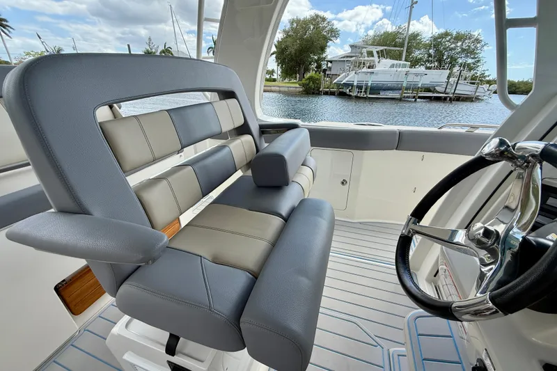 Slide: The Image of 2025 Boston Whaler 350 Realm interior with luxurious seating and steering wheel, docked by water. - 35