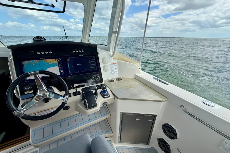 Slide: The Image of 2025 Boston Whaler 350 Realm helm with advanced navigation system, steering wheel, and ocean view. - 37