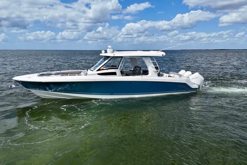 Slide: The Image of 2025 Boston Whaler 350 Realm boat cruising on open water under a partly cloudy sky. - 6