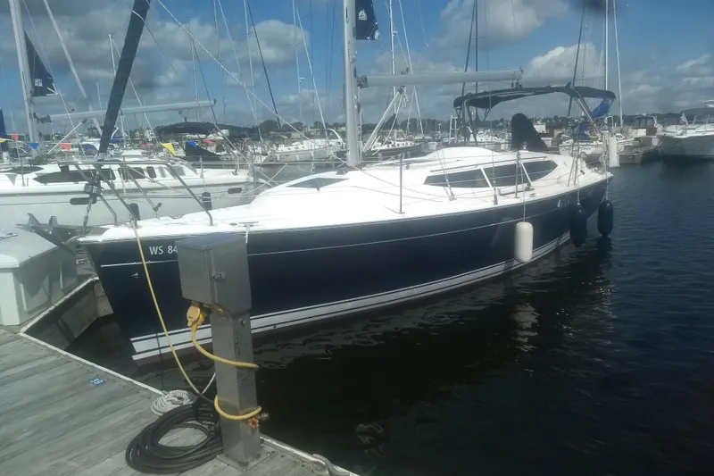 Slide: The Image of 2014 Marlow-Hunter 33 sailboat docked at a marina under a partly cloudy sky. - 2