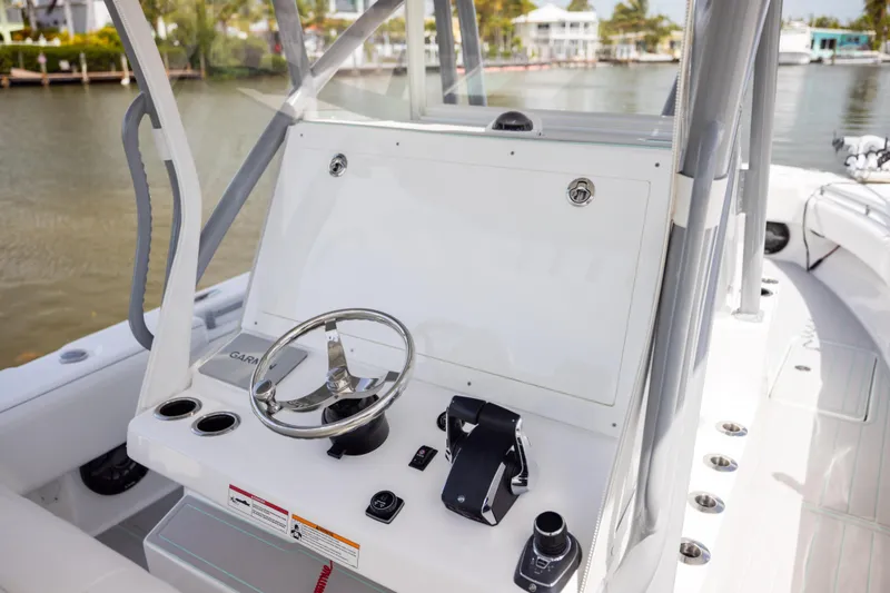 Slide: The Image of 2025 SeaHunter 30 Floridian boat console with steering wheel and controls, docked by the water. - 24