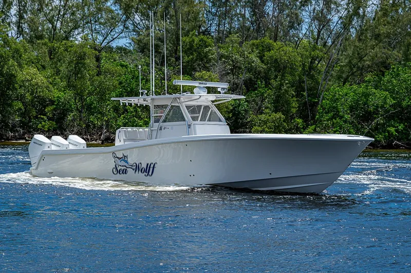 Slide: The Image of 2015 Invincible 42 Open Fisherman boat cruising on water, surrounded by lush greenery. - 25
