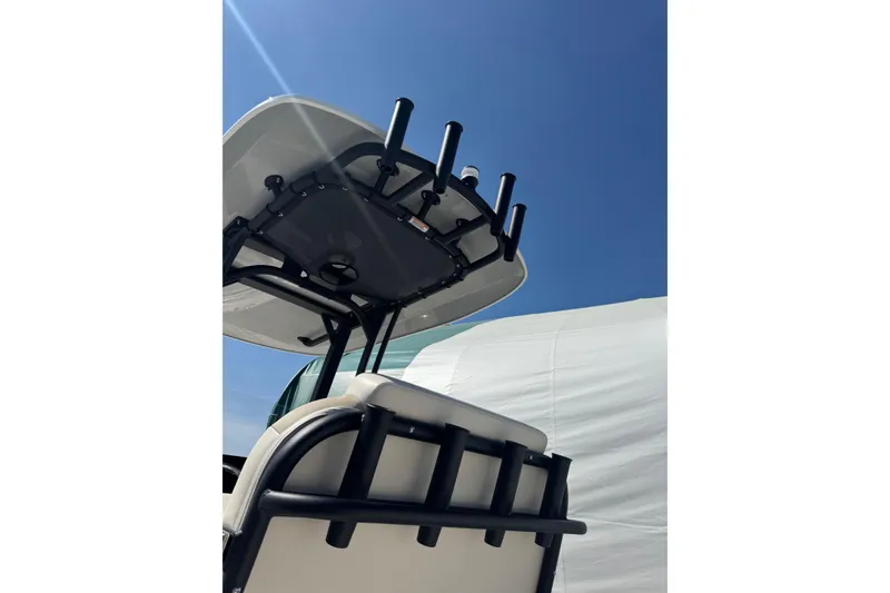 Slide: The Image of 2026 Boston Whaler 220 Dauntless boat with rod holders under a clear blue sky. - 12