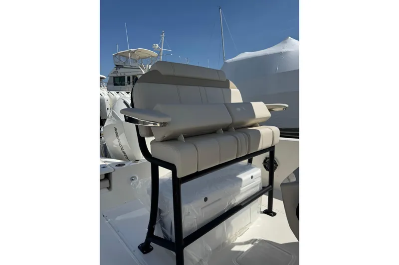 Slide: The Image of 2026 Boston Whaler 220 Dauntless boat seating with armrests, docked under clear sky. - 15