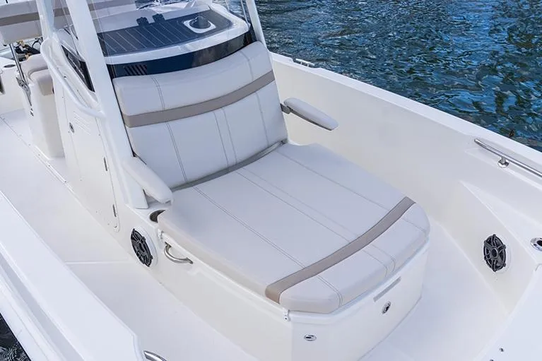 Slide: The Image of Manufacturer Provided Image: 2026 Boston Whaler 220 Dauntless boat interior with cushioned seating and water backdrop. - 2