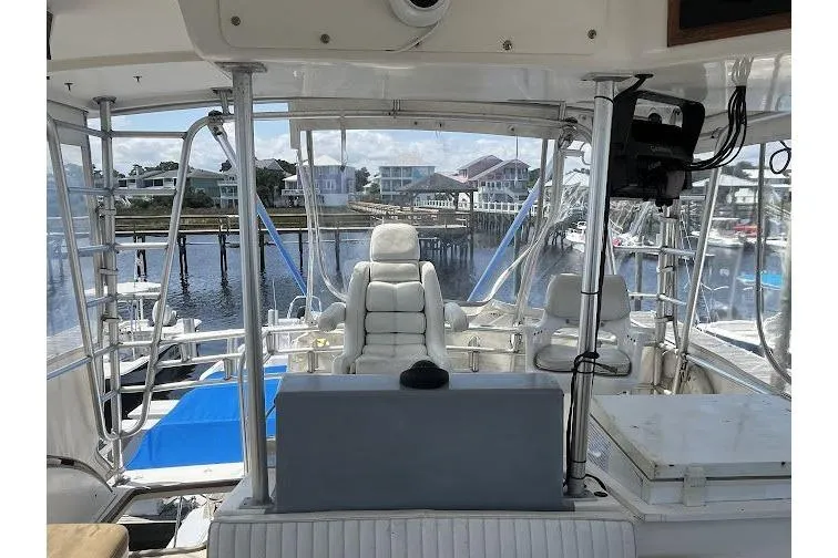 Slide: The Image of 1989 Topaz 44 Sportfisherman boat interior with marina view, featuring white seating and control panel. - 12