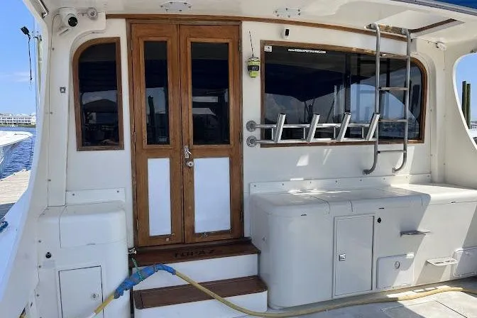 Slide: The Image of 1989 Topaz 44 Sportfisherman boat deck with wooden doors and fishing rod holders. - 5