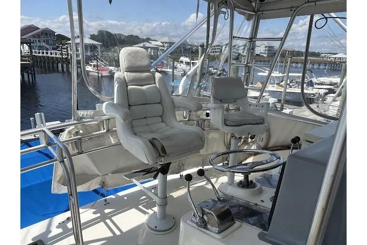 Slide: The Image of 1989 Topaz 44 Sportfisherman helm with cushioned captain chairs and marina view. - 7