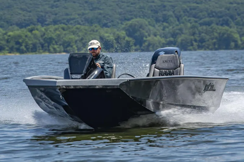 Slide: The Image of Manufacturer Provided Image: 2026 Excel EX 183 boat speeding on a lake with a driver, surrounded by lush greenery. - 1