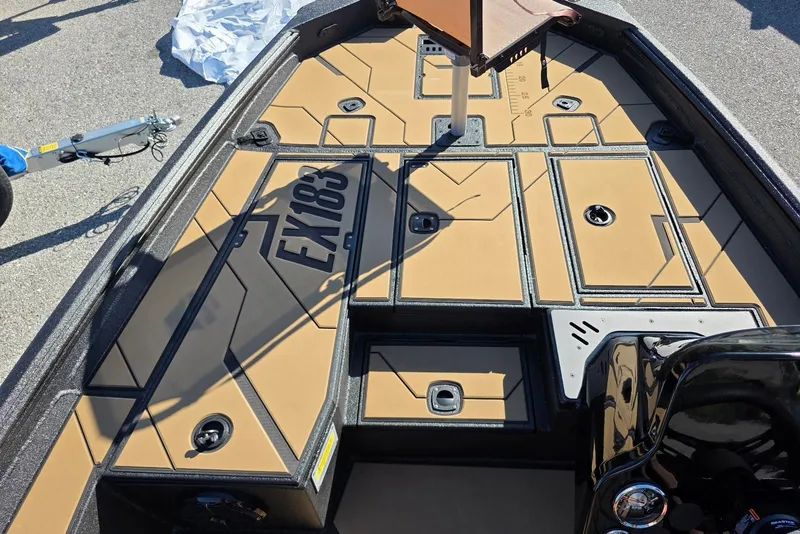 Slide: The Image of Excel EX 183 boat interior, 2026 model, featuring tan deck with storage compartments. - 15
