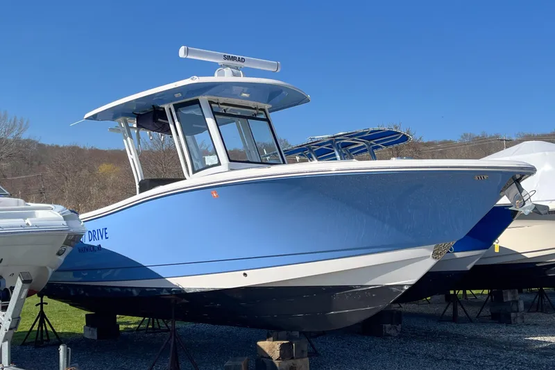 The Image of 2023 Robalo R270 Center Console boat in blue, displayed outdoors on stands. - 1